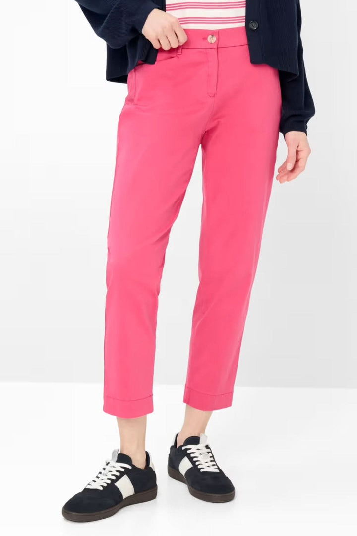 Person wearing Pantalon MARA cheville rose avec coupe ajustée et baskets noires et blanches.