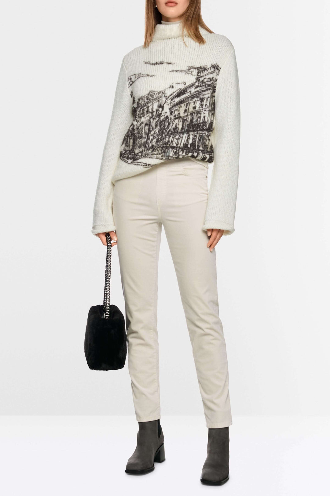 Femme portant un Pantalon Siena à taille élastique en coton extensible avec un pull blanc et des bottes.