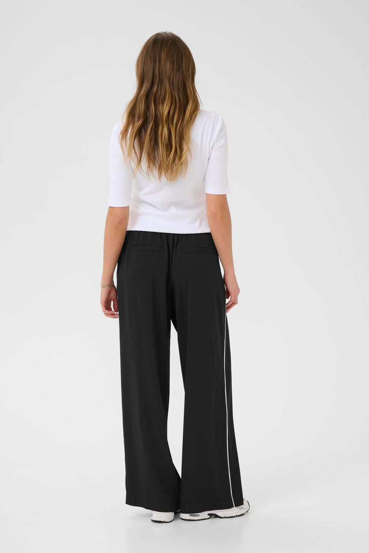 Femme vue de dos portant un pantalon Tessa fluide à jambe large avec un t-shirt blanc.