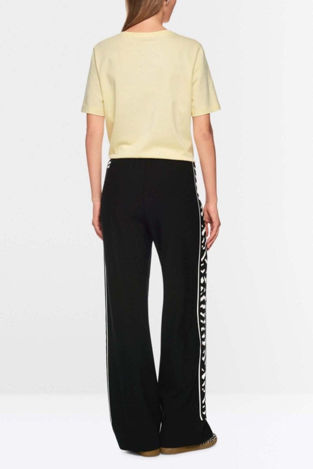 Femme portant le Pantalon WELKOM avec coupe large, taille élastiquée et bande latérale imprimé animalier, vu de dos.