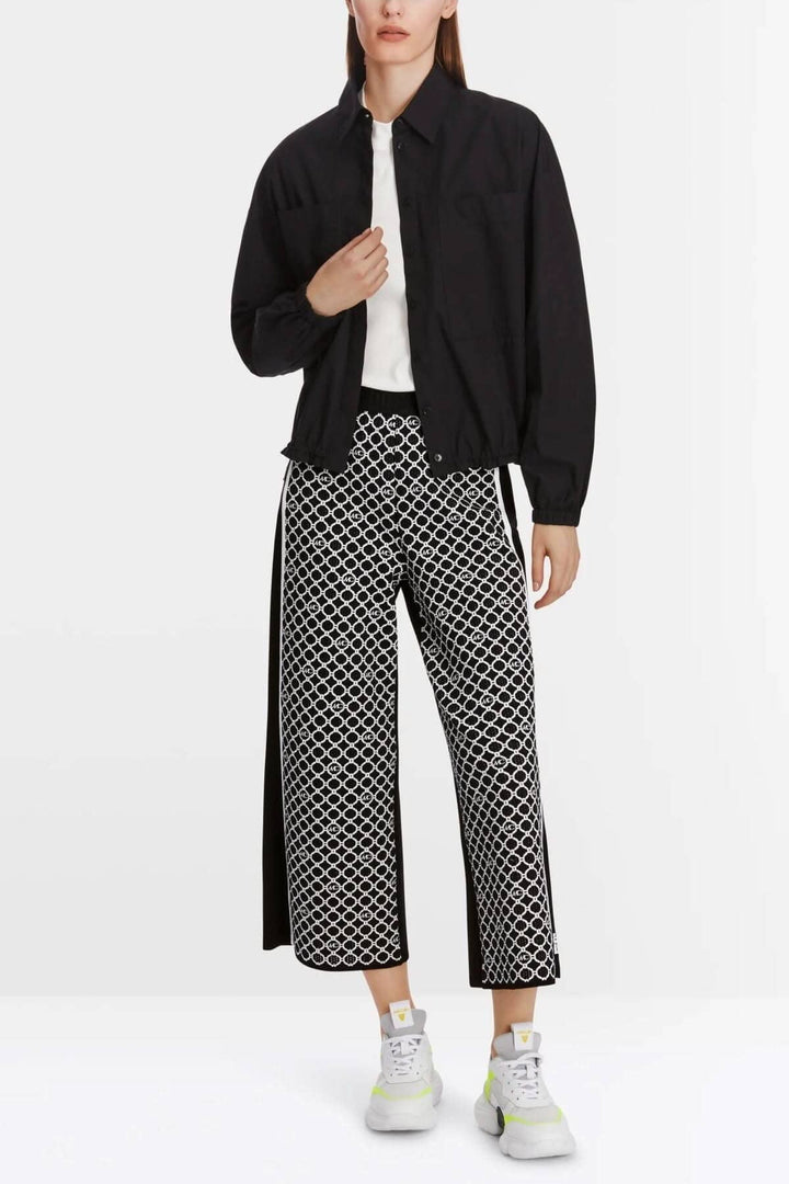 Femme portant un pantalon large WUSU à motif chaînes et une veste noire moderne.