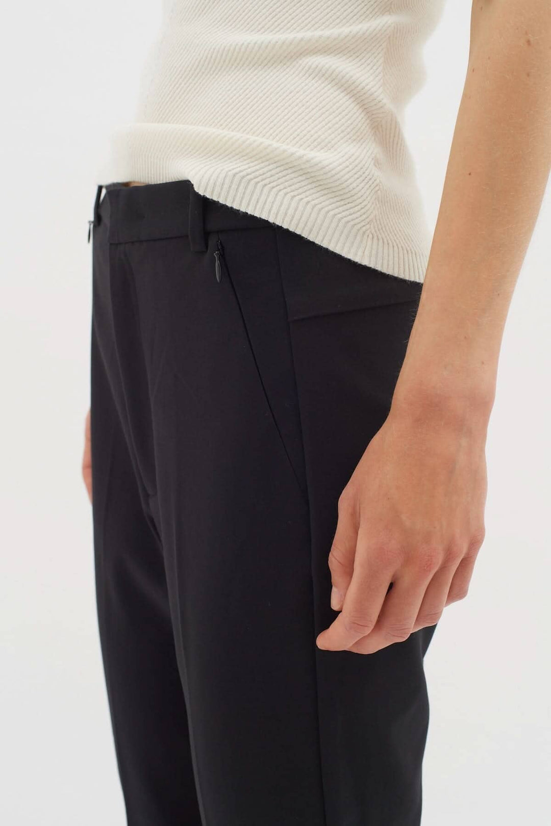 Pantalon Ziggi noir avec poches zippées, coupe ajustée et tissu en coton confortable, porté avec un haut blanc.