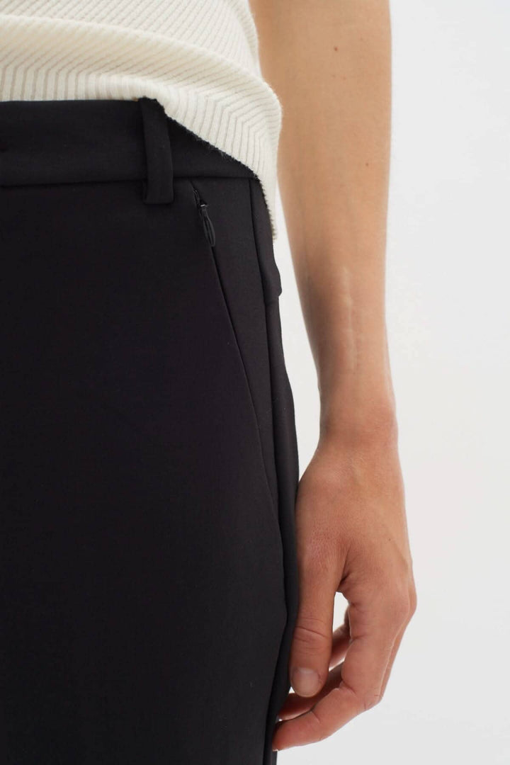Détail du pantalon Ziggi noir avec poches zippées et coupe ajustée, porté avec un haut à rayures.