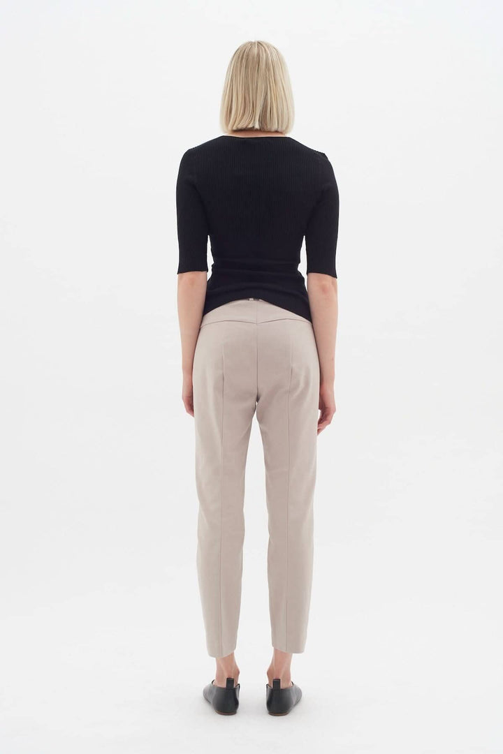 Femme vue de dos portant le pantalon Ziggi beige, avec un haut noir élégant et des chaussures noires.