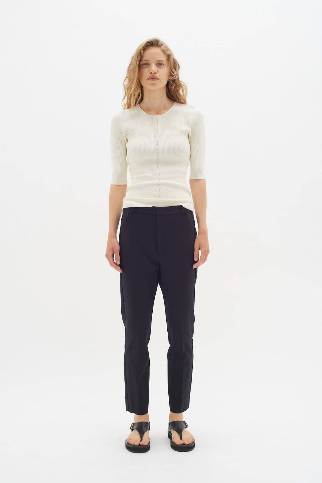 Femme portant un pantalon Ziggi noir en coton, associé à un haut beige, style décontracté et élégant.