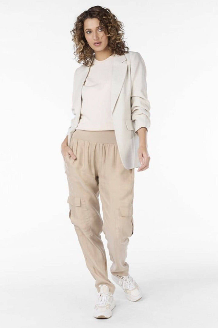 Femme portant un pantalon cargo beige avec une veste, combiné avec des chaussures blanches pour un look décontracté.