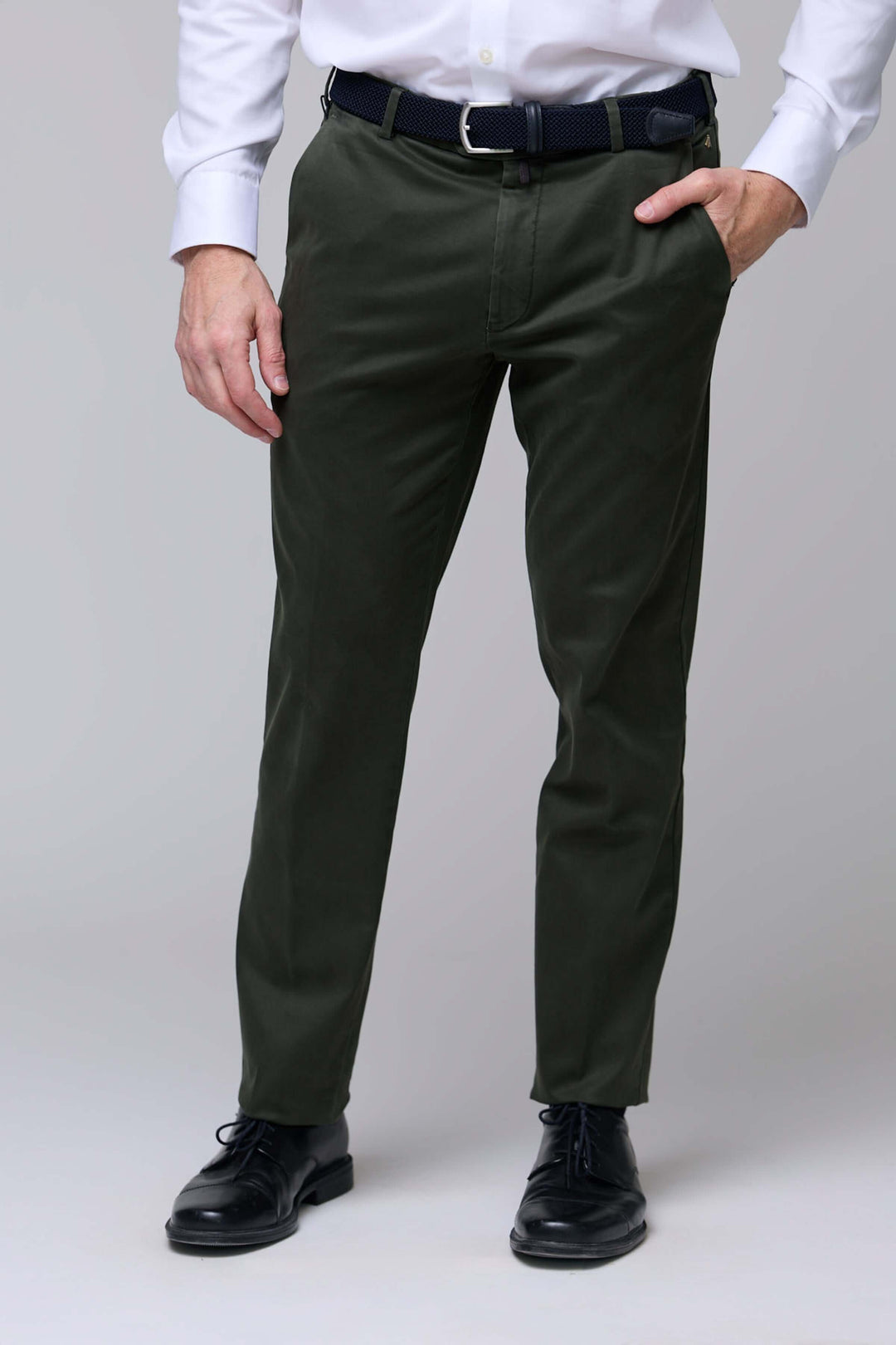 Pantalon chino ajusté vert porté avec chemise blanche et chaussures noires, coupe moderne et confortable.