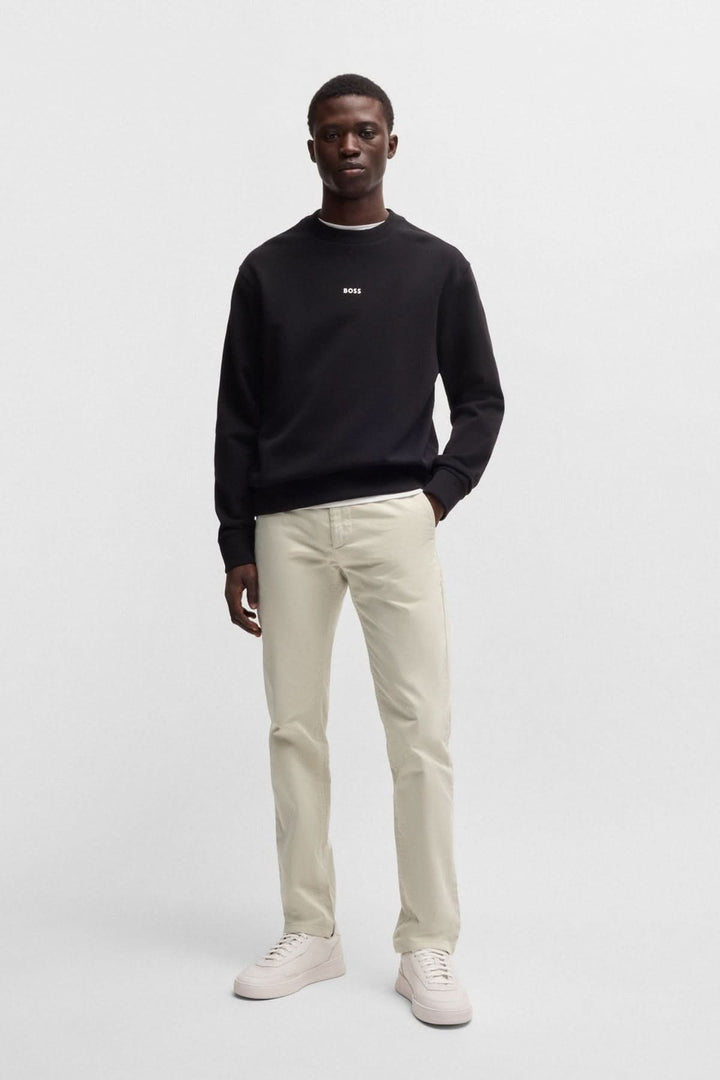 Homme en pantalon chino slim beige et sweat noir, style moderne et décontracté, idéal pour une tenue élégante.