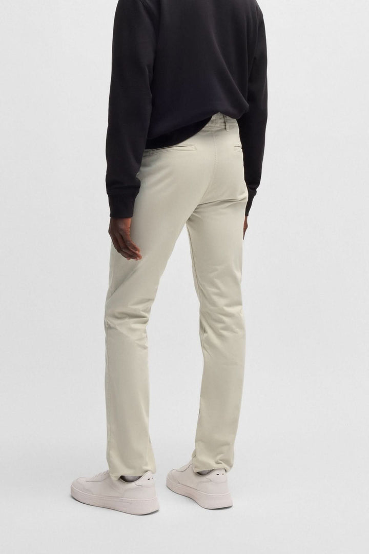 Pantalon chino slim beige porté de dos avec un haut noir, offrant un look moderne et élégant.