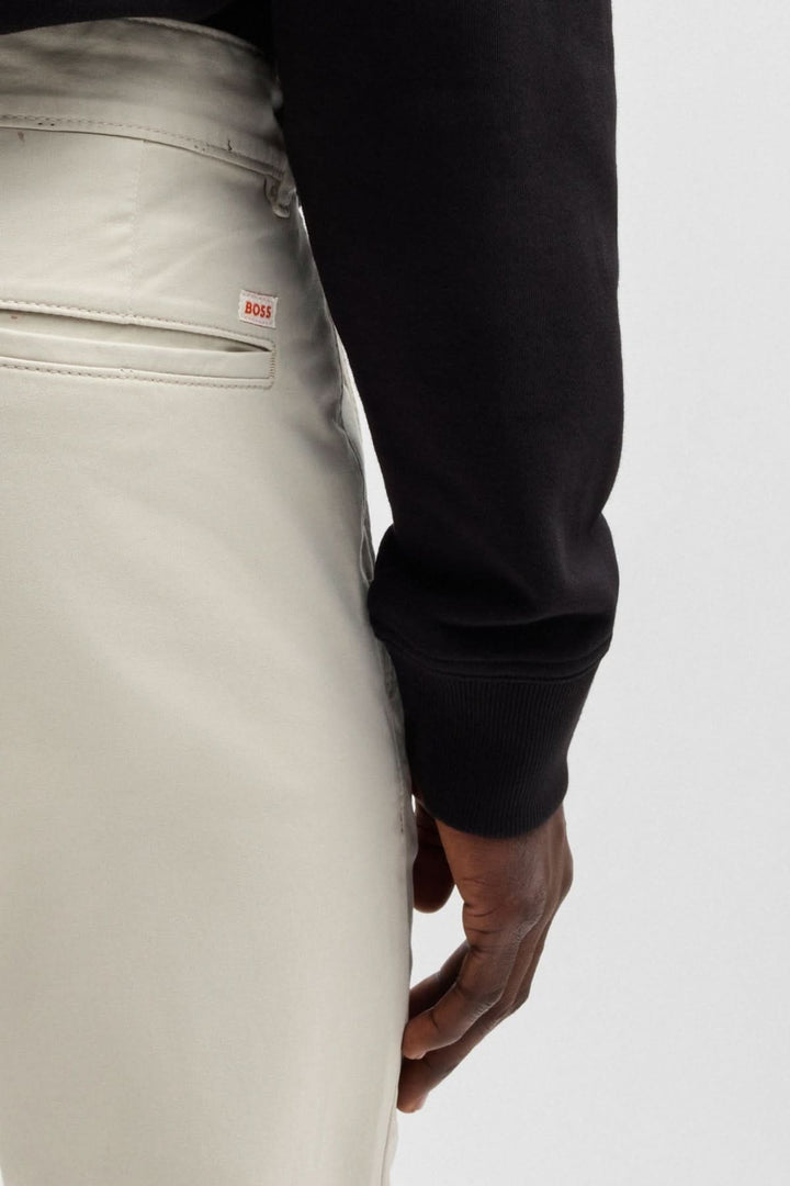Détail sur un pantalon chino slim de BOSS, mettant en valeur le tissu extensible et la coupe ajustée.