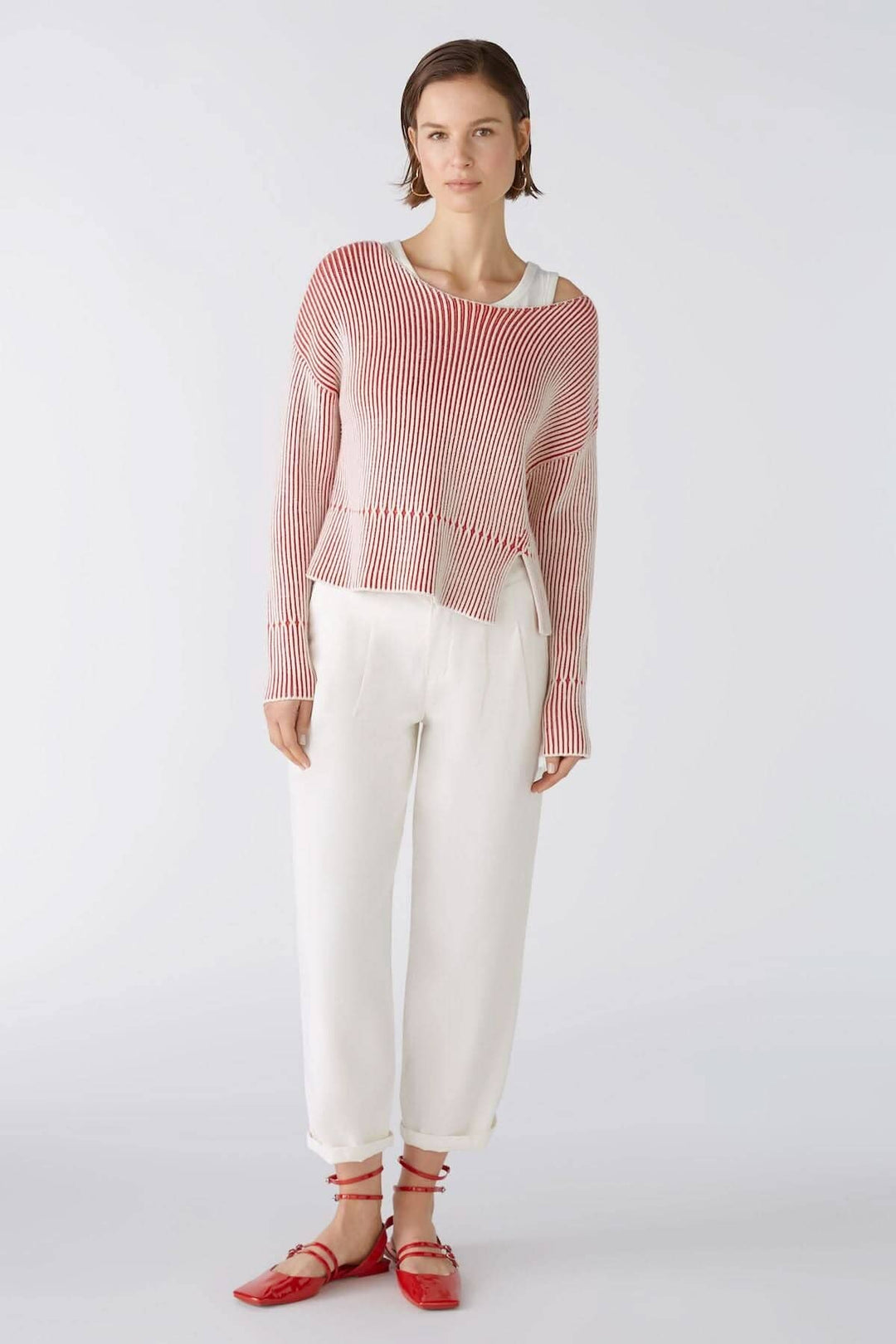 Femme portant un pull rayé rouge et blanc avec un pantalon blanc, stylé et décontracté.