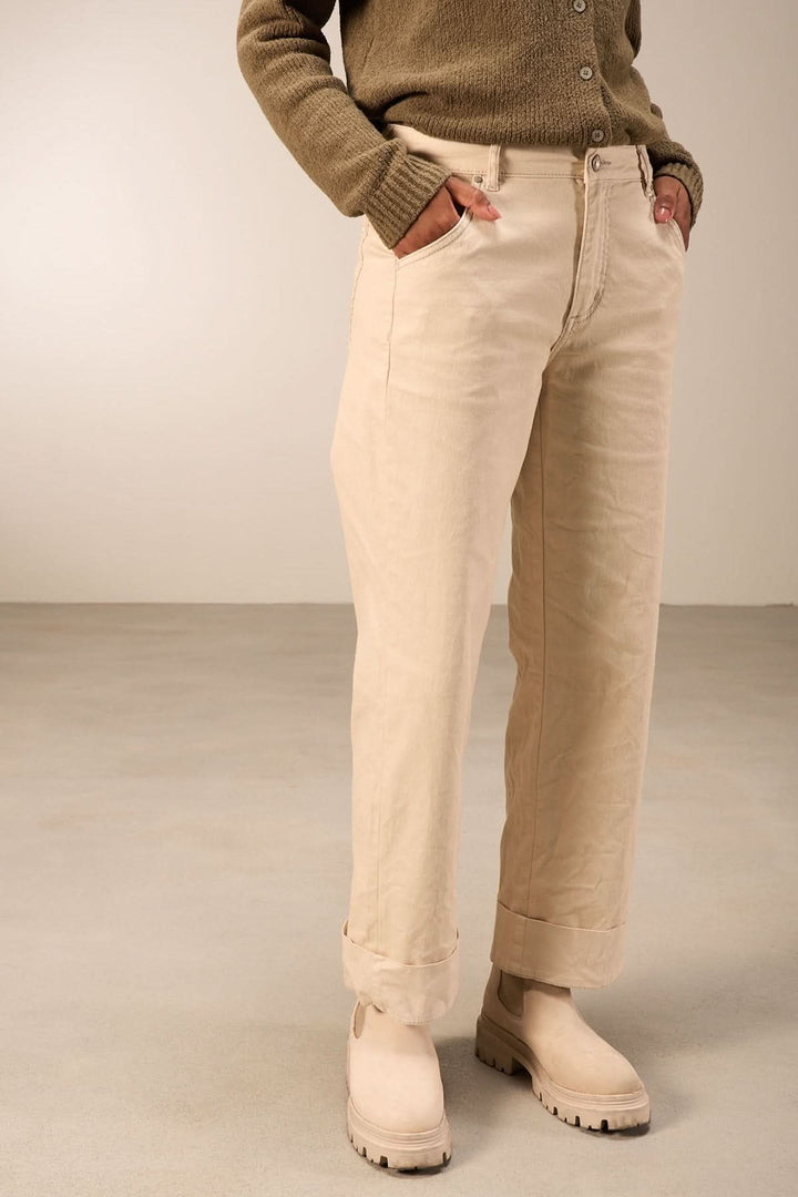 Person wearing pantalon droit beige, coupe droite décontractée, taille mi-haute, associé à un chandail en maille et bottines.