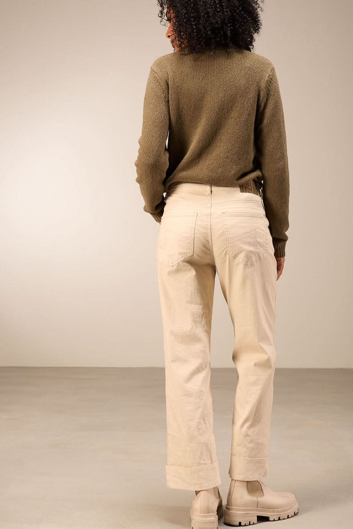 Pantalon droit beige à coupe droite, porté avec un chandail kaki, montrant une allure décontractée et moderne pour un style quotidien.