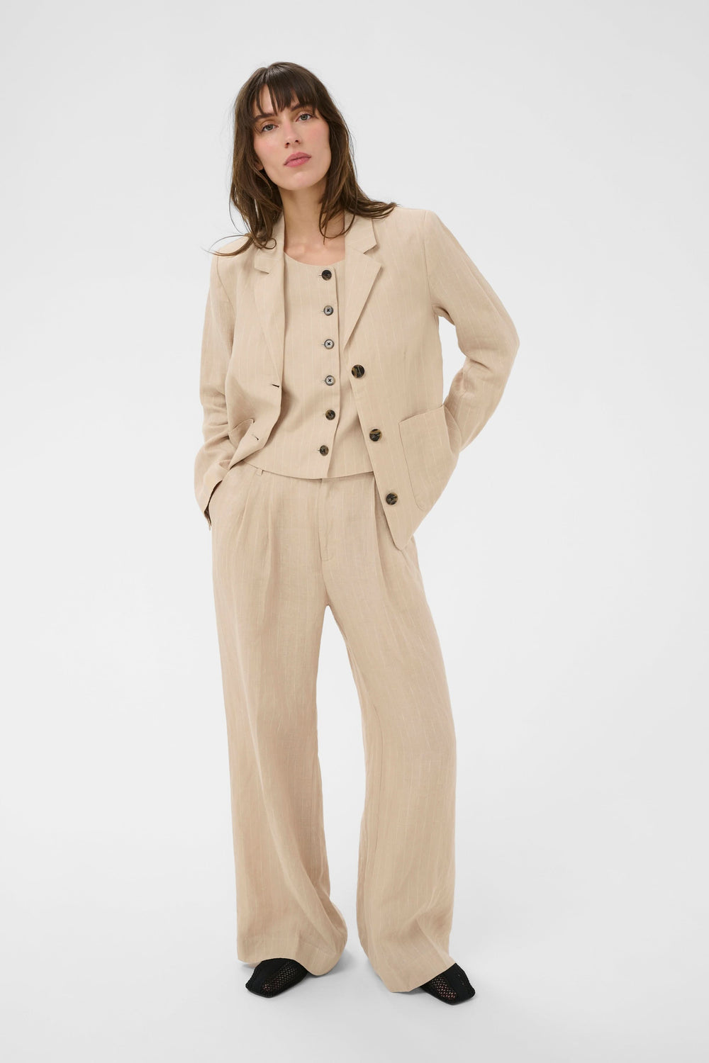 Femme portant un ensemble élégant incluant le Pantalon en lin Aliya, coupe droite et plis à l'avant, parfait pour la saison chaude.