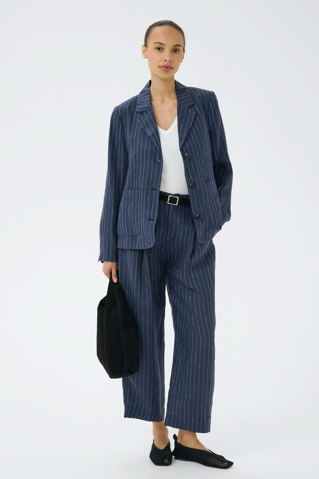 Femme portant un ensemble élégant en lin rayé avec pantalon en lin Aliya et veste assortie, parfait pour un look professionnel raffiné.