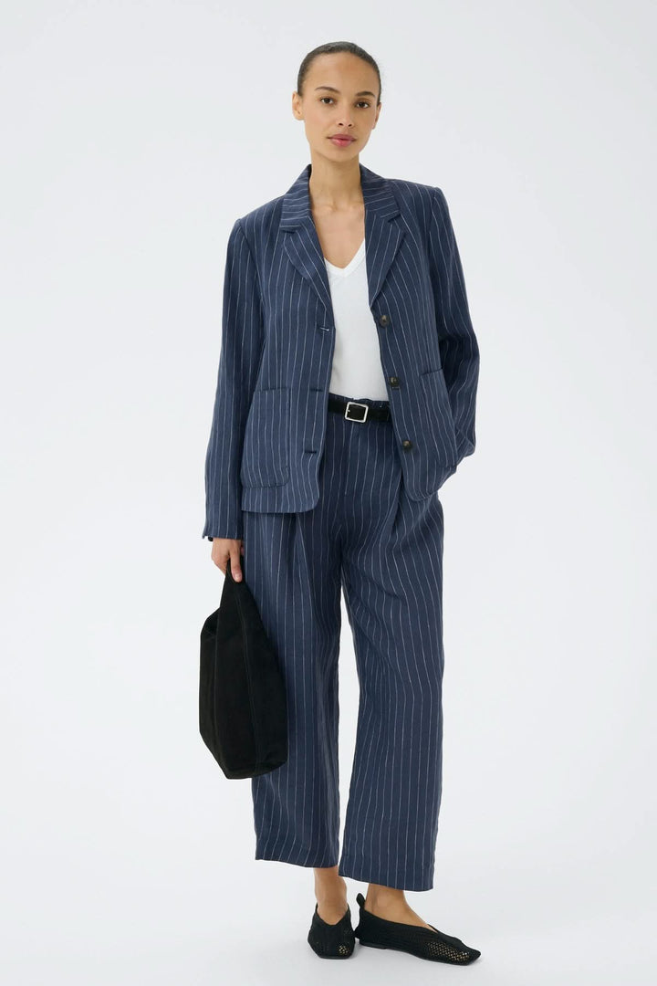 Femme portant un ensemble élégant en lin rayé avec pantalon en lin Aliya et veste assortie, parfait pour un look professionnel raffiné.