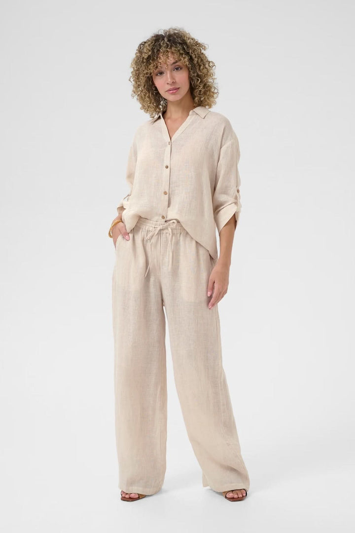 Pantalon en lin léger avec taille élastique, associé à une blouse fluide pour un look décontracté et naturel.