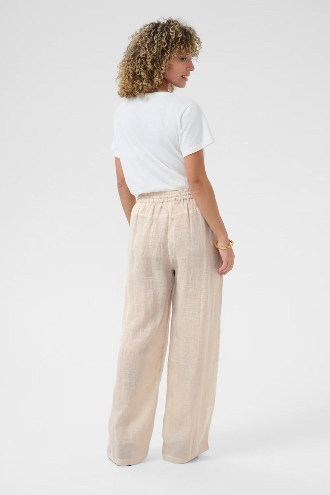 Femme portant un pantalon en lin léger avec taille élastique, vue de dos, tissu respirant et souple.