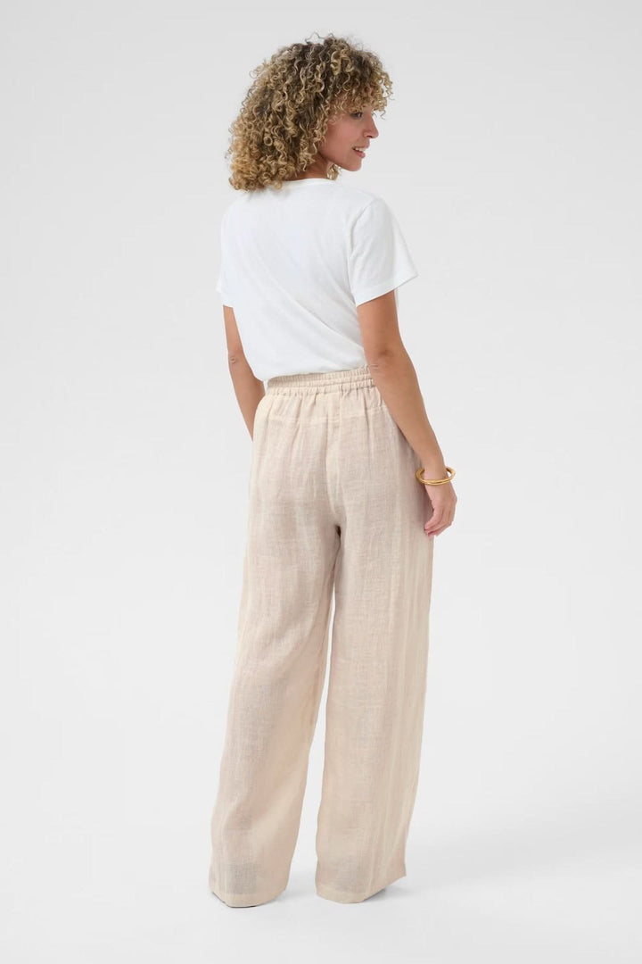 Femme portant un pantalon en lin léger avec taille élastique, vue de dos, tissu respirant et souple.