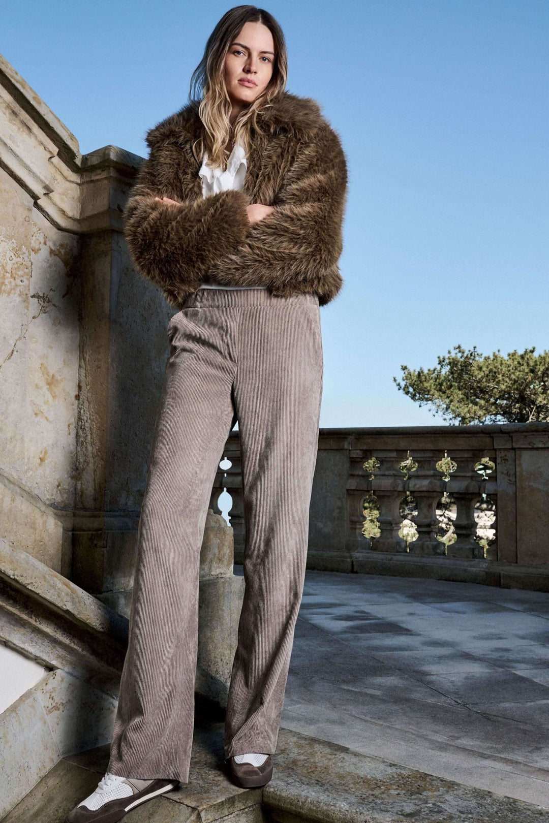 Modèle portant un pantalon en velours côtelé à jambe large, cadre extérieur élégant, produit pour un look rétro sophistiqué.
