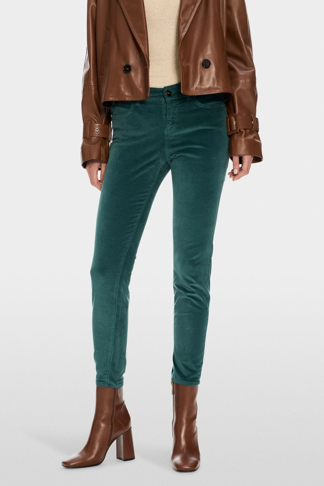 Pantalon en velours vert foncé slim avec une jambe raccourcie, porté avec un blouson en cuir marron.