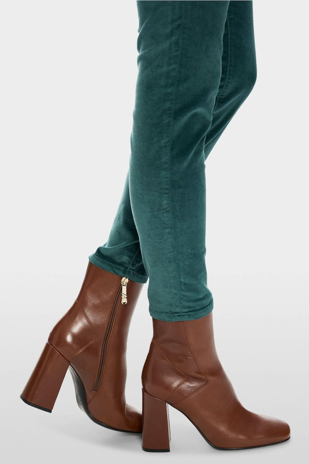 Pantalon en velours vert avec bottines en cuir brun à talons, style décontracté et élégant.