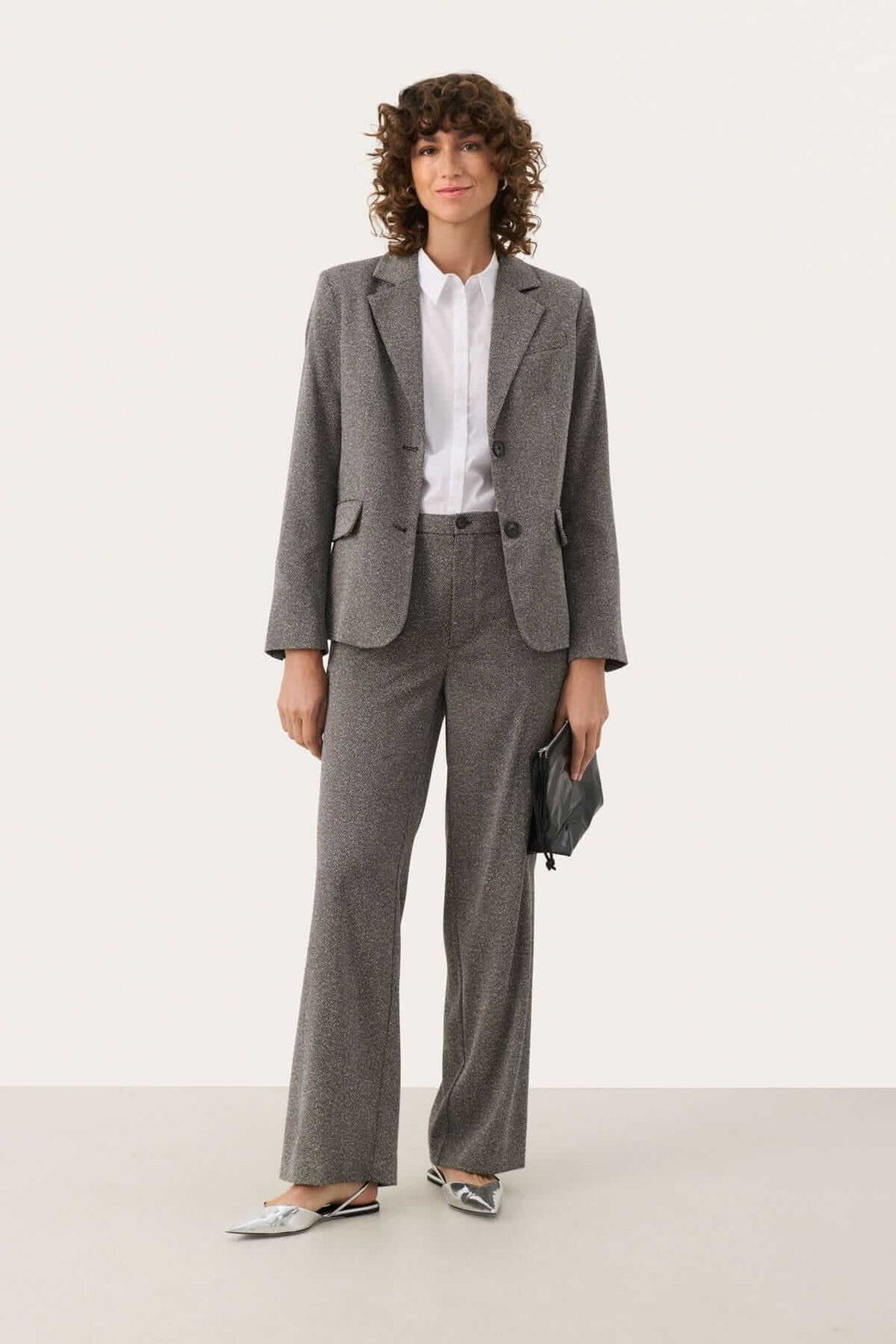 Femme en pantalon habillé gris avec blazer sur une tenue chic, parfaite pour le travail et les occasions formelles.