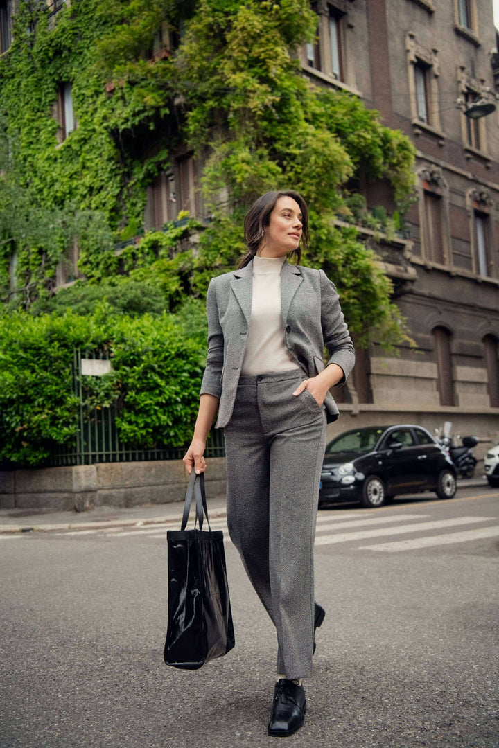 Femme portant un pantalon habillé Linora à jambe large, élégante en ville avec un sac noir.