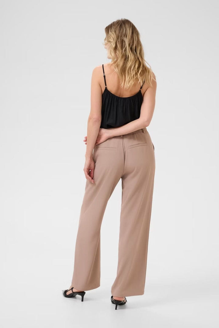 Pantalon à jambe large beige, en coupe fluide, porté avec un top noir, vue arrière.