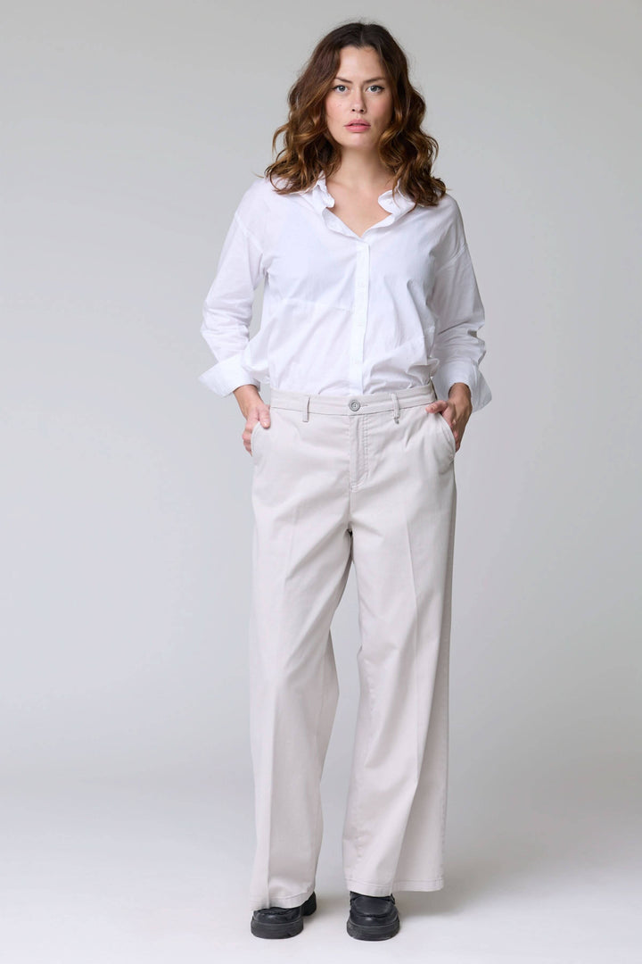 Femme portant un pantalon à jambe large, élégant et décontracté, avec poches latérales et ourlets nets. Tissu fluide et confortable.