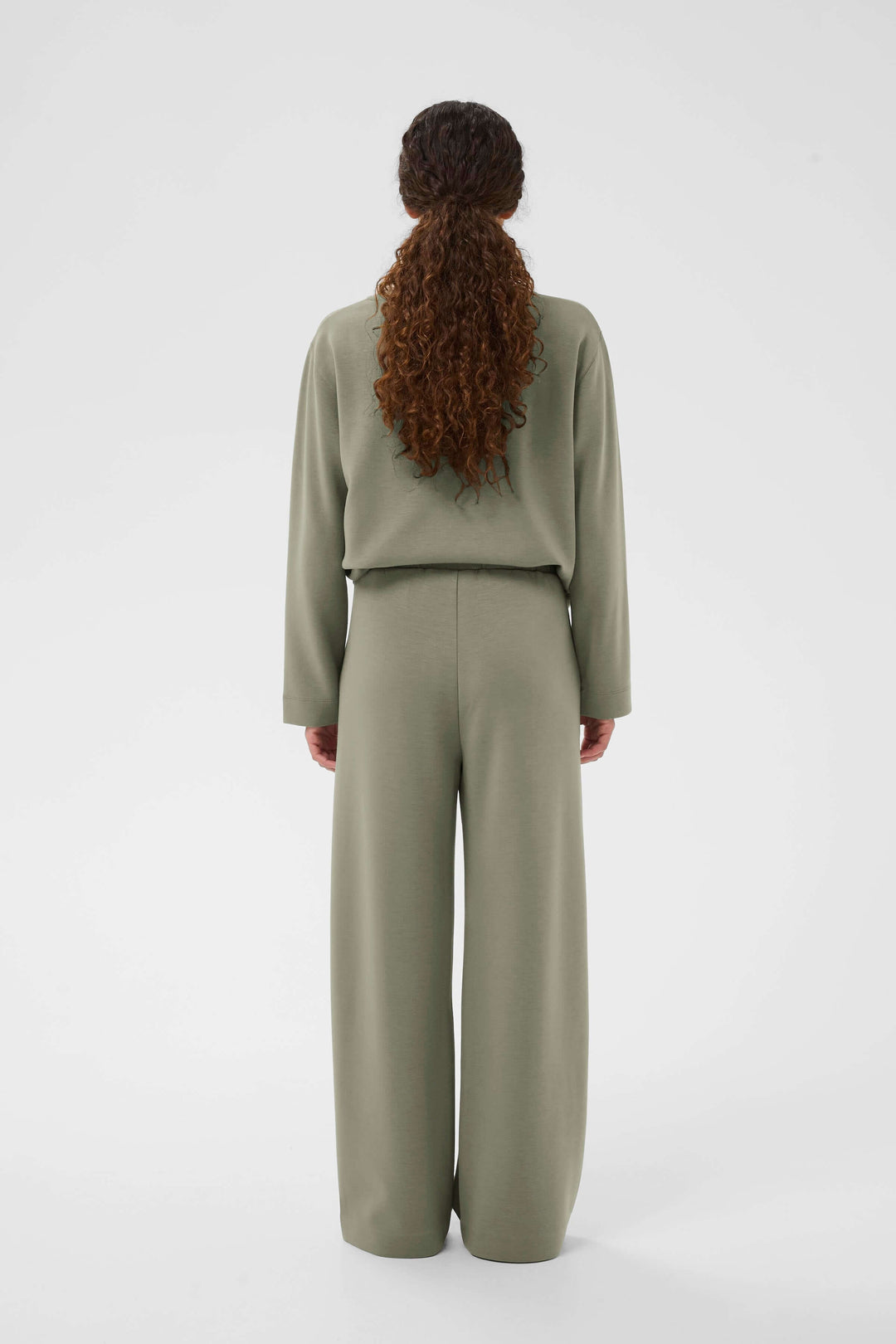 Femme portant un pantalon à jambe large Gincette, style épuré et contemporain, vue arrière.