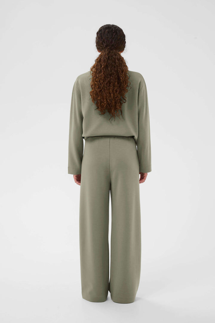 Femme portant un pantalon à jambe large Gincette, style épuré et contemporain, vue arrière.