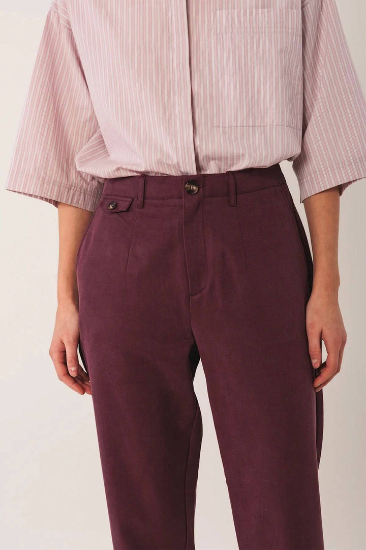Pantalon à la coupe droite en tissu texturé, portant une chemise rayée pour un look moderne et confortable.