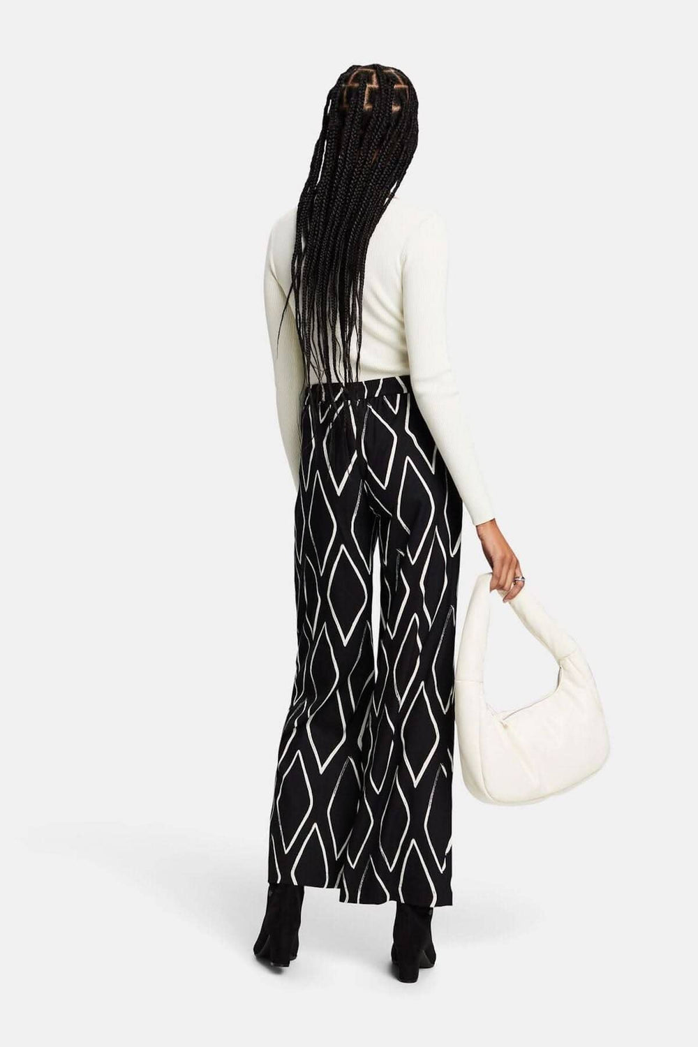Pantalon large à enfiler imprimé losanges, porté avec un haut clair et un sac à main blanc.