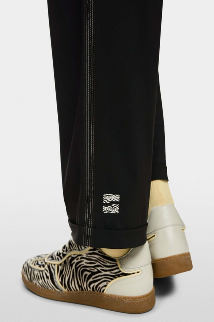 Pantalon léger WUXI avec ourlet retourné et bande latérale, détails sportifs, éco-responsable, vu avec chaussures à motif zébré.