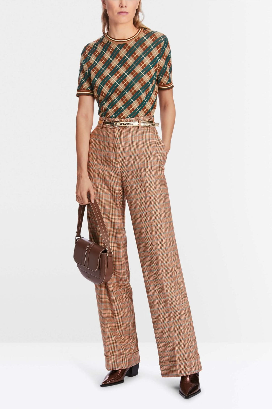 Femme portant un pantalon à motifs avec une jambe large, associé à un haut à rayures et un sac chic.