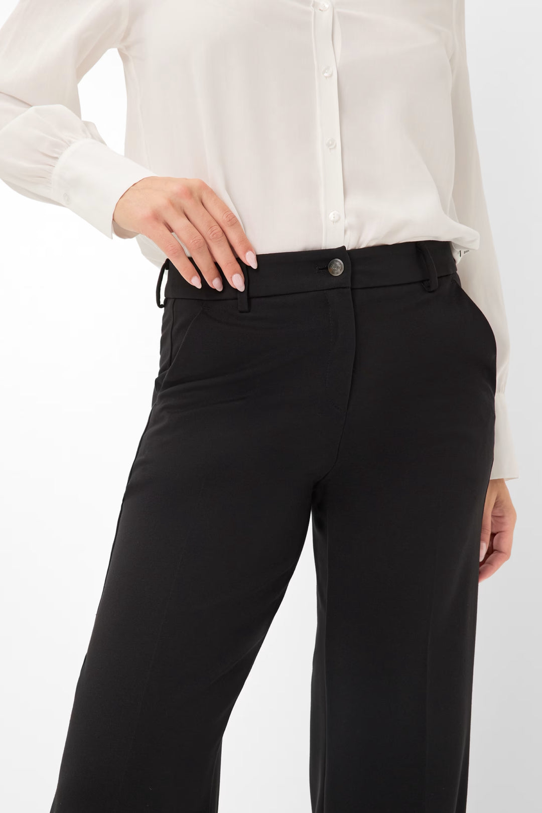 Pantalon palazzo noir avec taille mi-haute, porté avec une chemise blanche élégante.