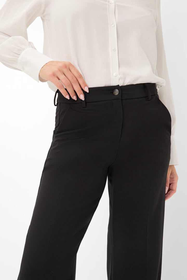 Pantalon palazzo noir avec taille mi-haute, porté avec une chemise blanche élégante.