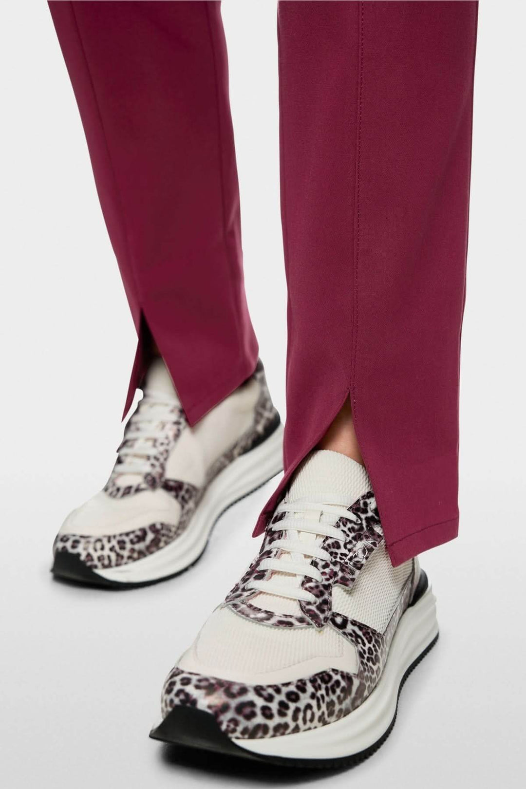 Pantalon pull-on SIENA coupe slim en tissu extensible avec fentes frontales, porté avec des baskets à motif léopard.