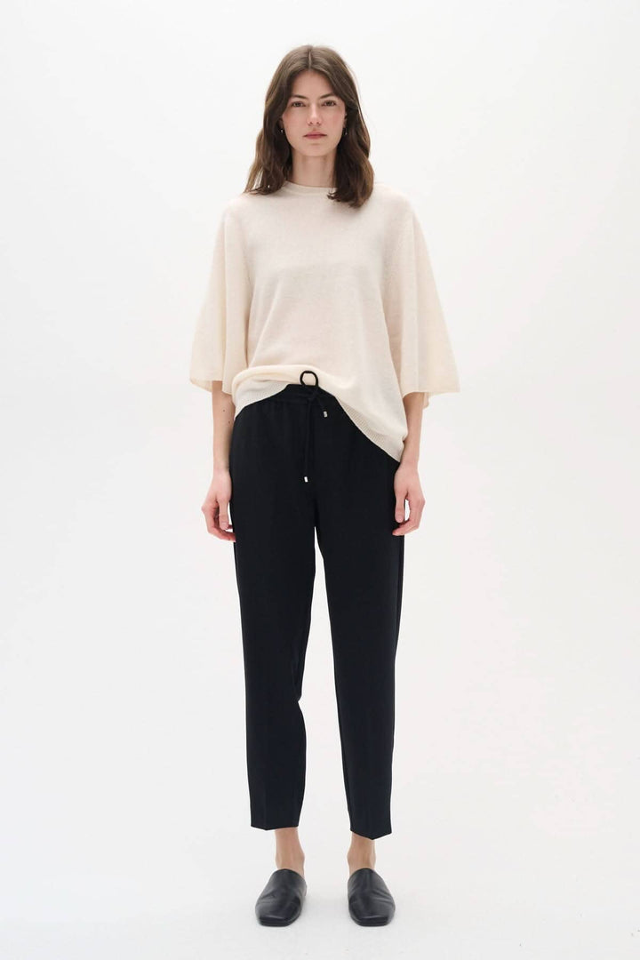 Femme portant un pantalon Adian noir inspiré du jogger, associé à un haut beige, dans un look décontracté.
