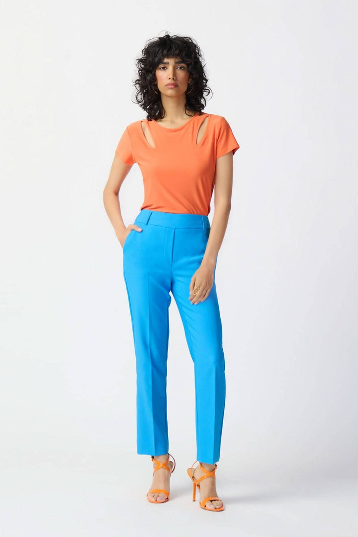 Femme portant un pantalon tailleur droit bleu avec un haut orange, créant un look moderne et décontracté.