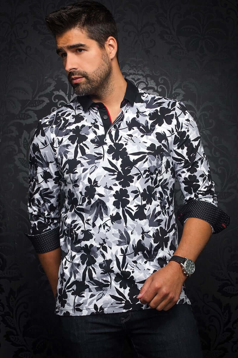 Homme portant un polo à manches longues avec motif floral abstrait en noir et blanc, col contrastant et poignets boutonnés.
