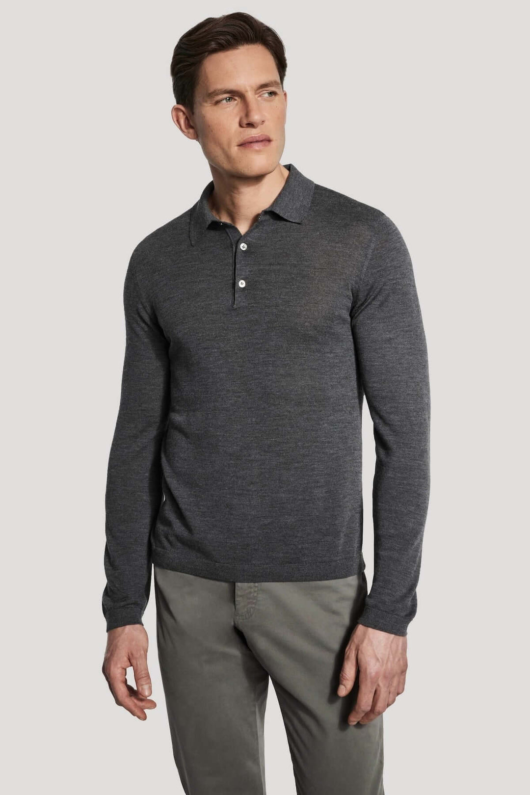 Homme portant un polo manches longues en laine mérinos et soie de couleur gris. Polo élégant et moderne pour confort optimal.