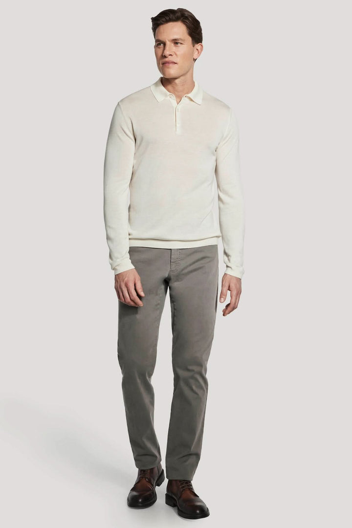 Homme portant un polo manches longues en laine mérinos et soie, coupe ajustée, couleur blanche.