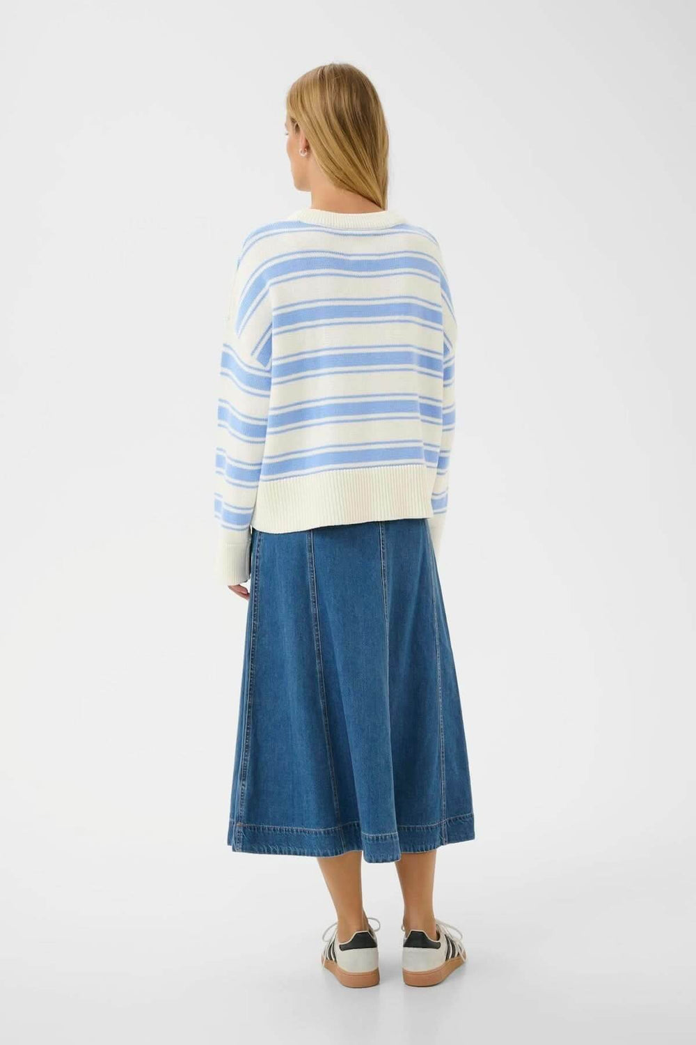 Femme portant un Pull à rayures Serafine bleu et blanc, coupe droite, parfait pour une tenue décontractée et élégante en journée fraîche.