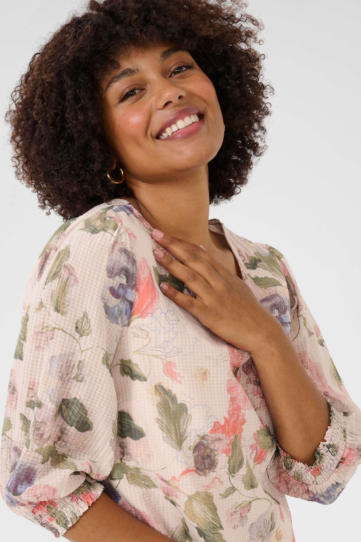 Femme souriante portant une robe fluide à imprimé floral, mettant en avant l&
