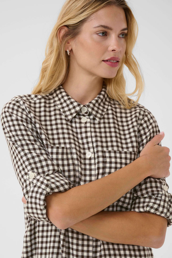 Femme portant la Robe Sardias à carreaux, manches retroussables, coupe droite et col classique. Style décontracté et moderne.