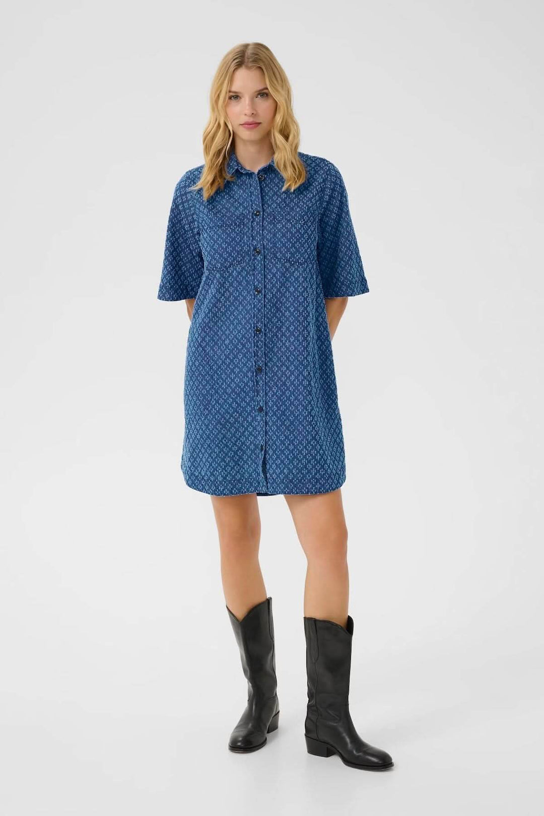 Femme portant une robe-chemise en denim léger avec motifs géométriques, manches courtes et col chemise, pour un look estival décontracté.