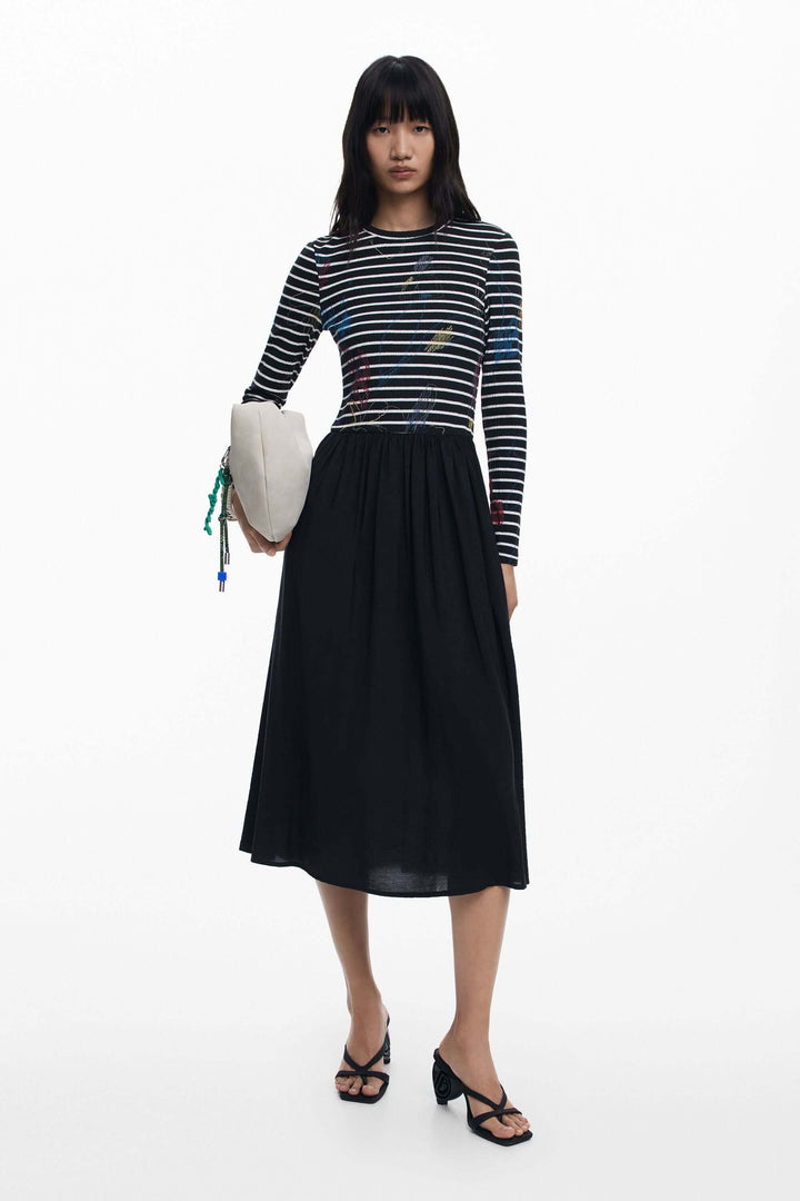 Robe combinée à rayures avec haut graphique et jupe fluide, portée par une femme, style chic et moderne, sandales à talon noires.