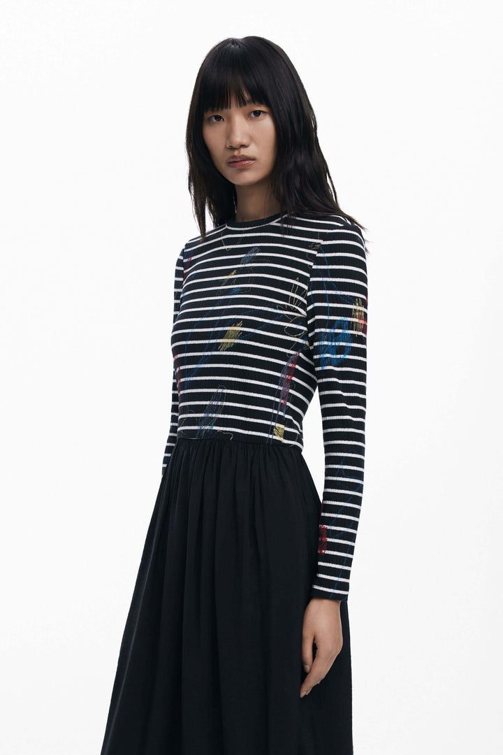 Robe combinée à rayures avec haut graphique à manches longues et jupe fluide noire, parfaite pour un style moderne et élégant.